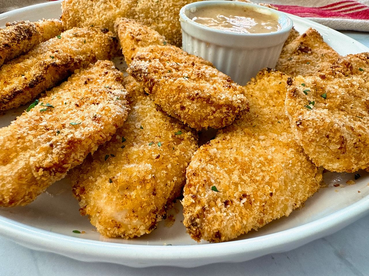 baked chicken fingers and honey mustard dip on a white plate