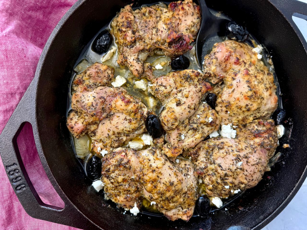 chicken thighs in a cast iron skillet with feta and olives