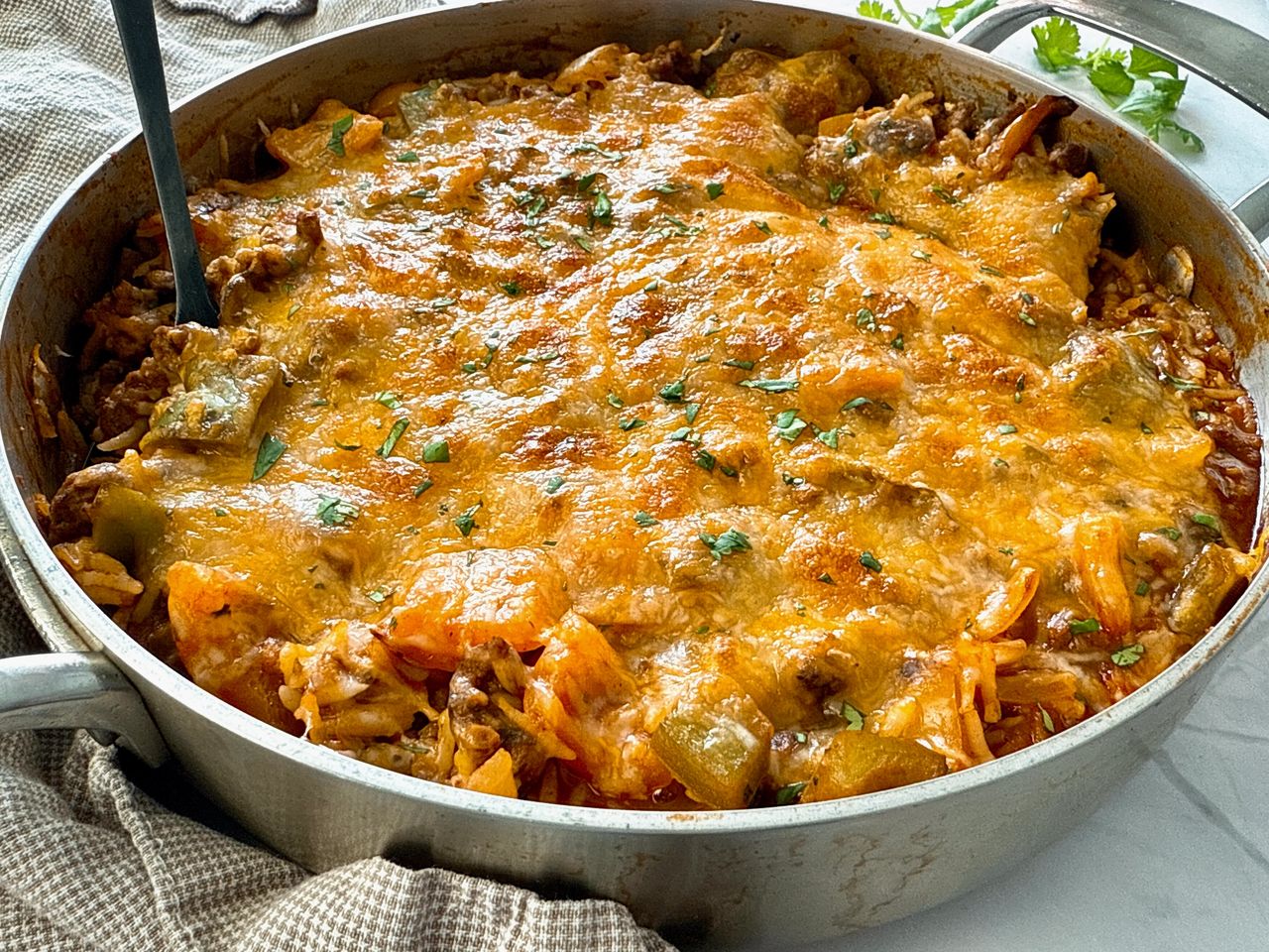 ground beef and rice covered with melted cheddar cheese in a deep skillet