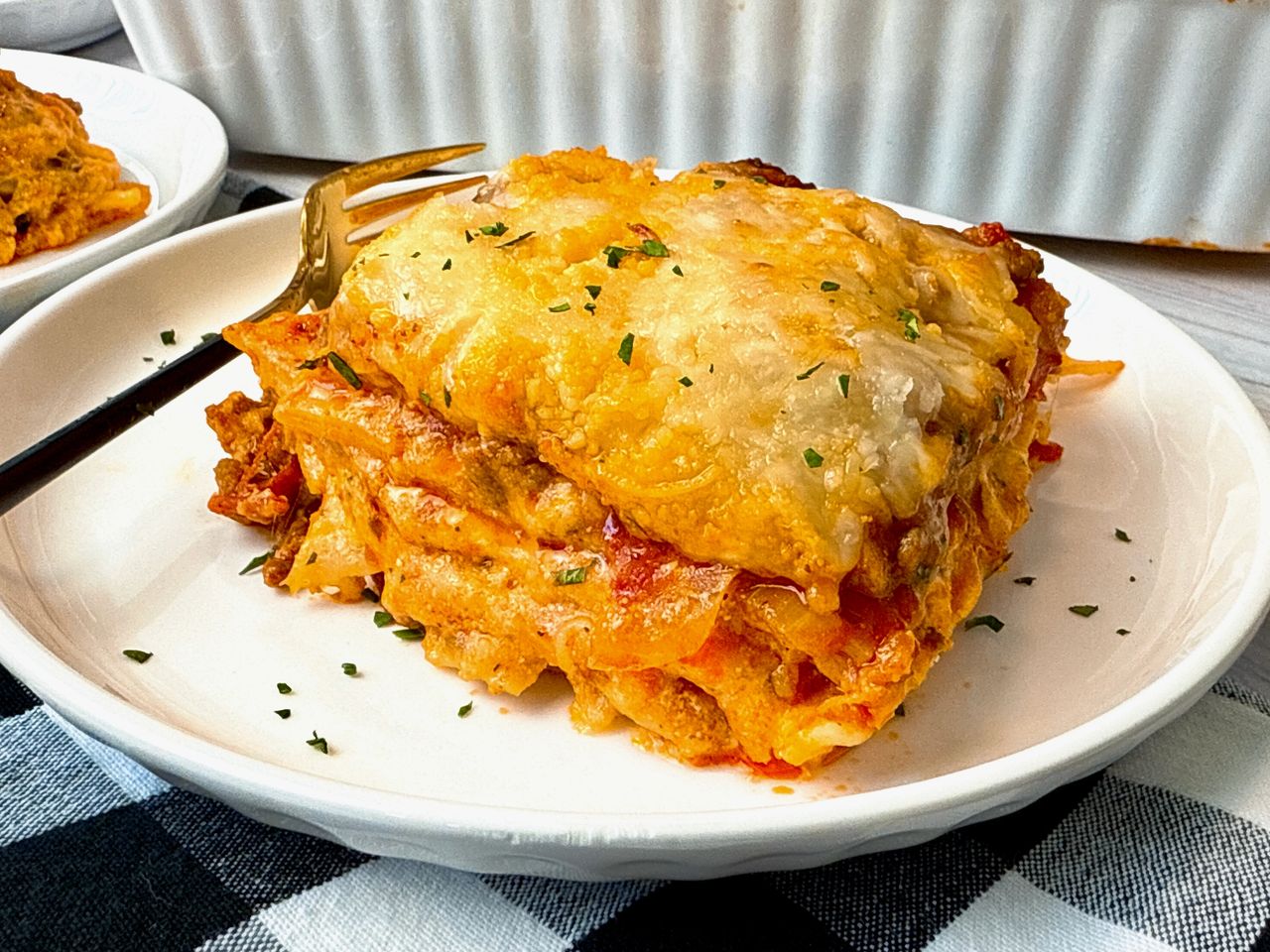 slice of lasagna on a white plate with a fork