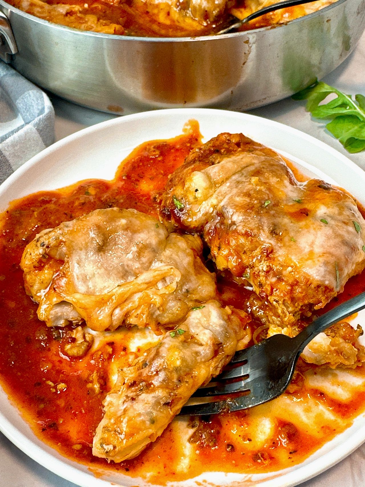 chicken thighs and marinara sauce with cheese in a pan