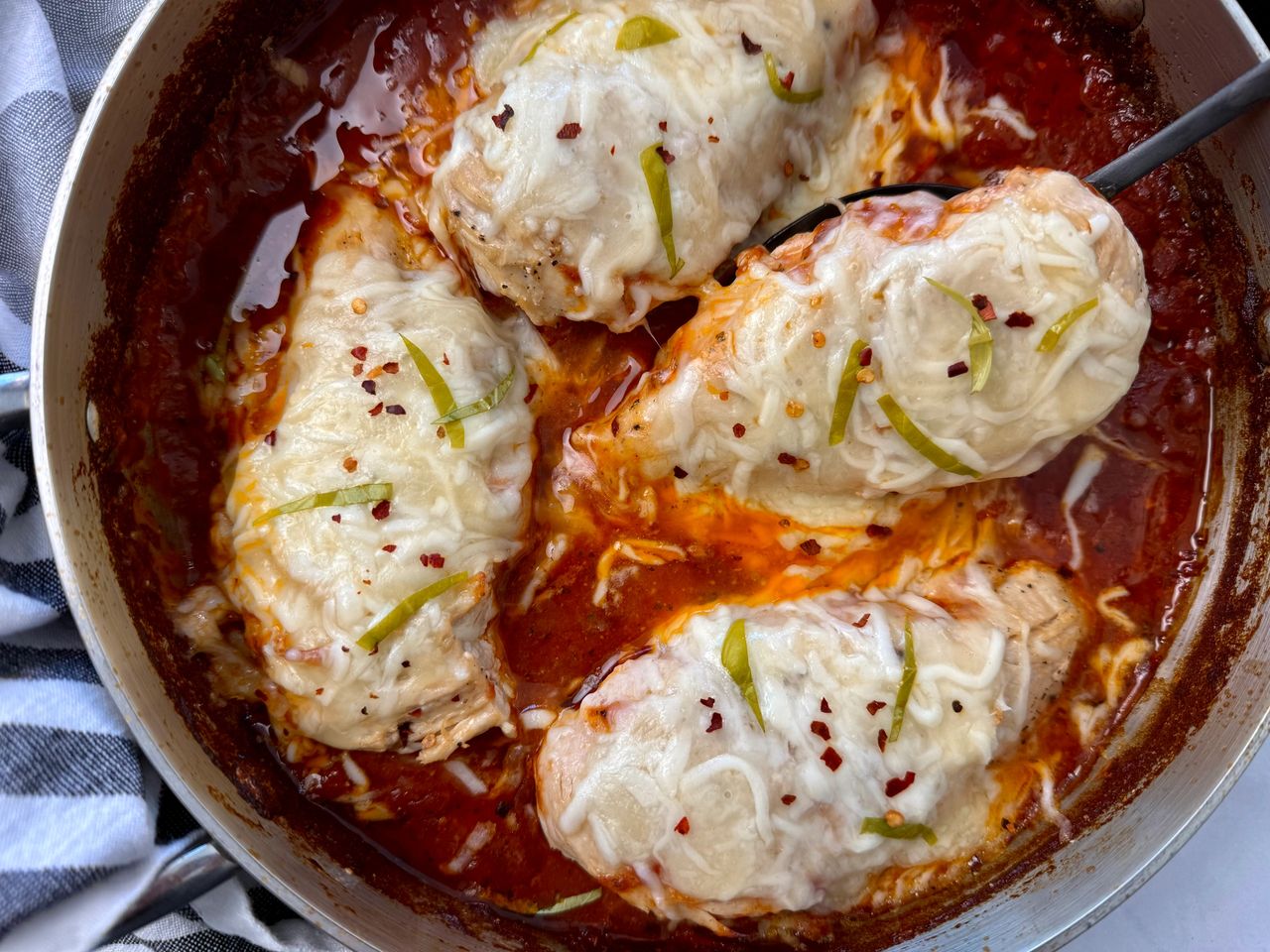 Baked Mozzarella Chicken chicken with marinara sauce and cheese in a deep skillet