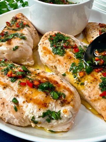 grilled chicken with chimichurri sauce on a white plate