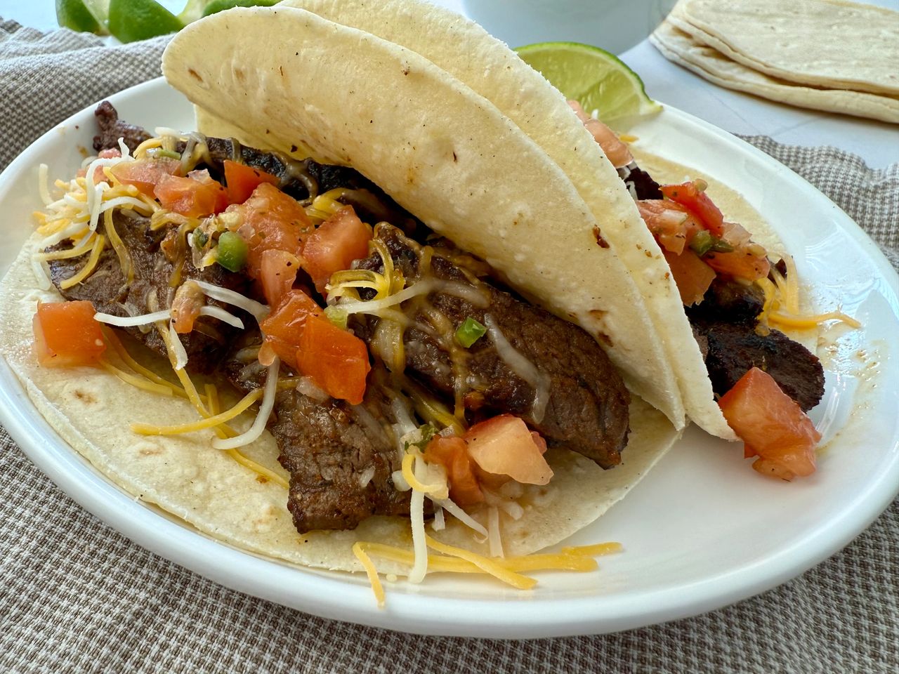 steak street tacos on a white plate with lime garnish