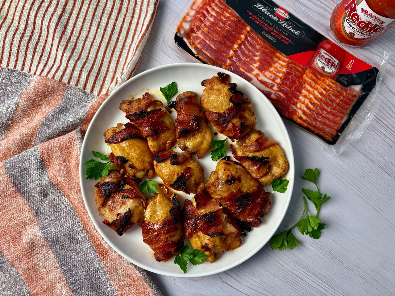 bacon wrapped chicken on a white plate with parsley garnish