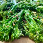 broccolini and red pepper flakes on a parchment paper lined baking sheet