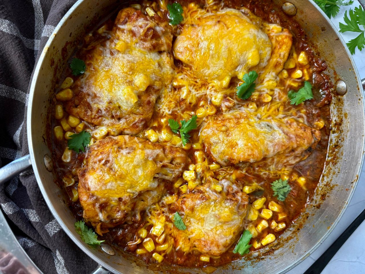 salsa chicken with cheese in a silver pan with a black spoon