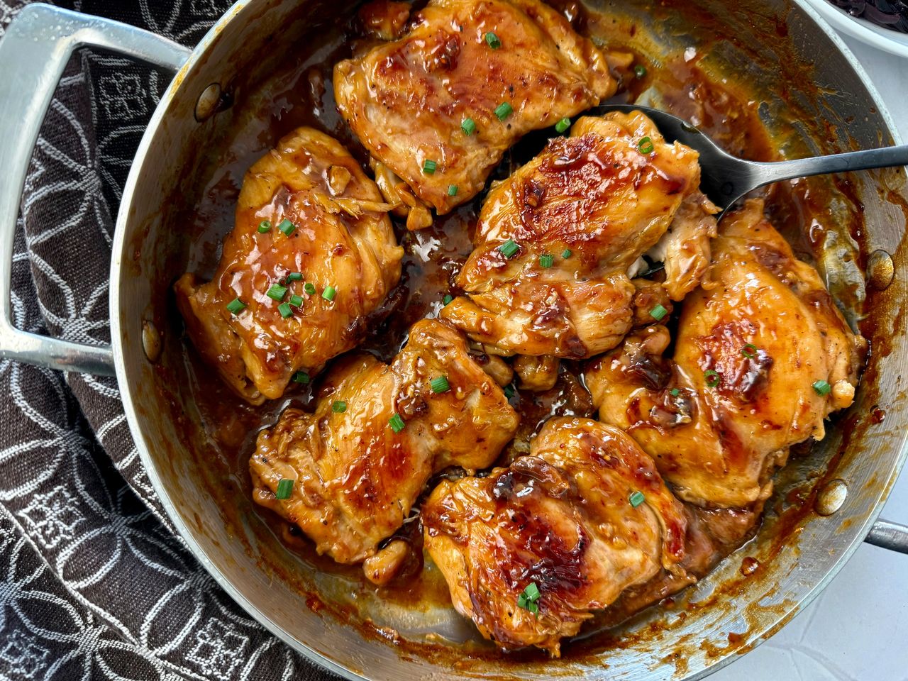Teriyaki Chicken Thighs teriyaki chicken in a pan with a serving spoon