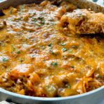 ground beef and rice covered with melted cheddar cheese in a deep skillet