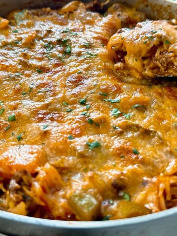 ground beef and rice covered with melted cheddar cheese in a deep skillet