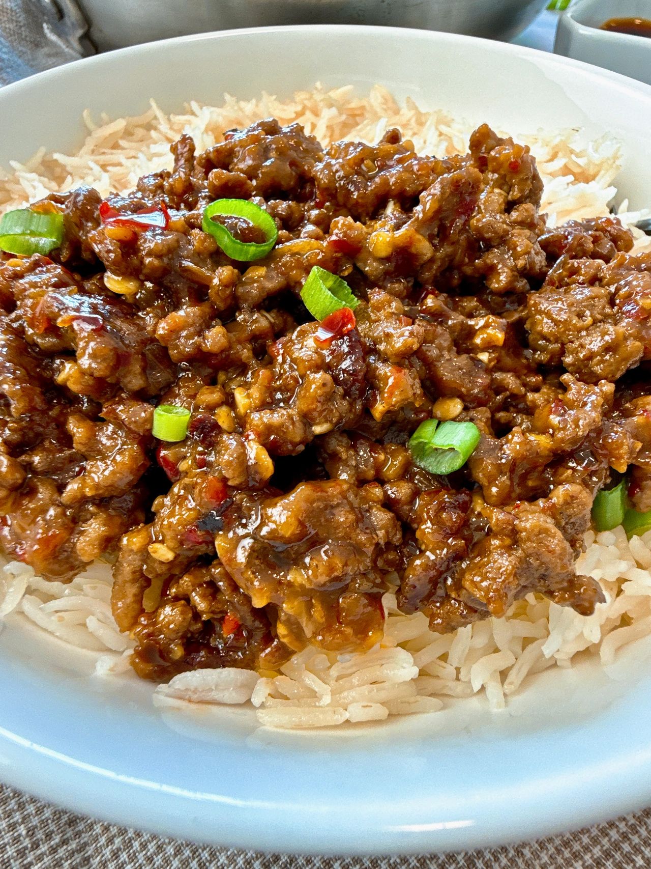Ground beef and chili crisp over rice in a white bowl