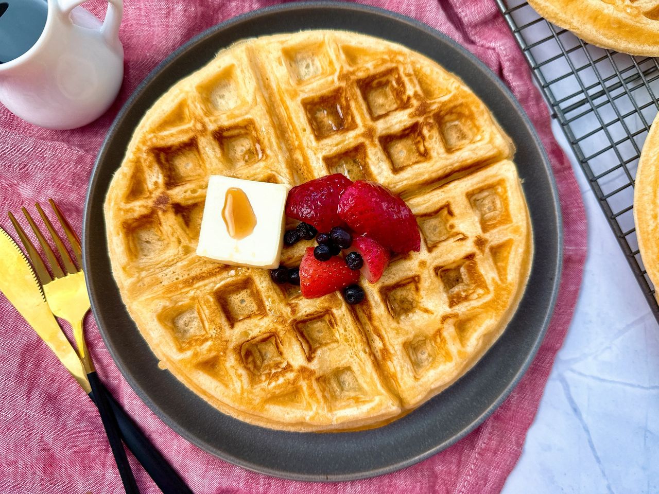 waffles on a grey plate with berries and butter
