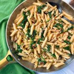 penne pasta, spinach, and sun dried tomatoes in a skillet