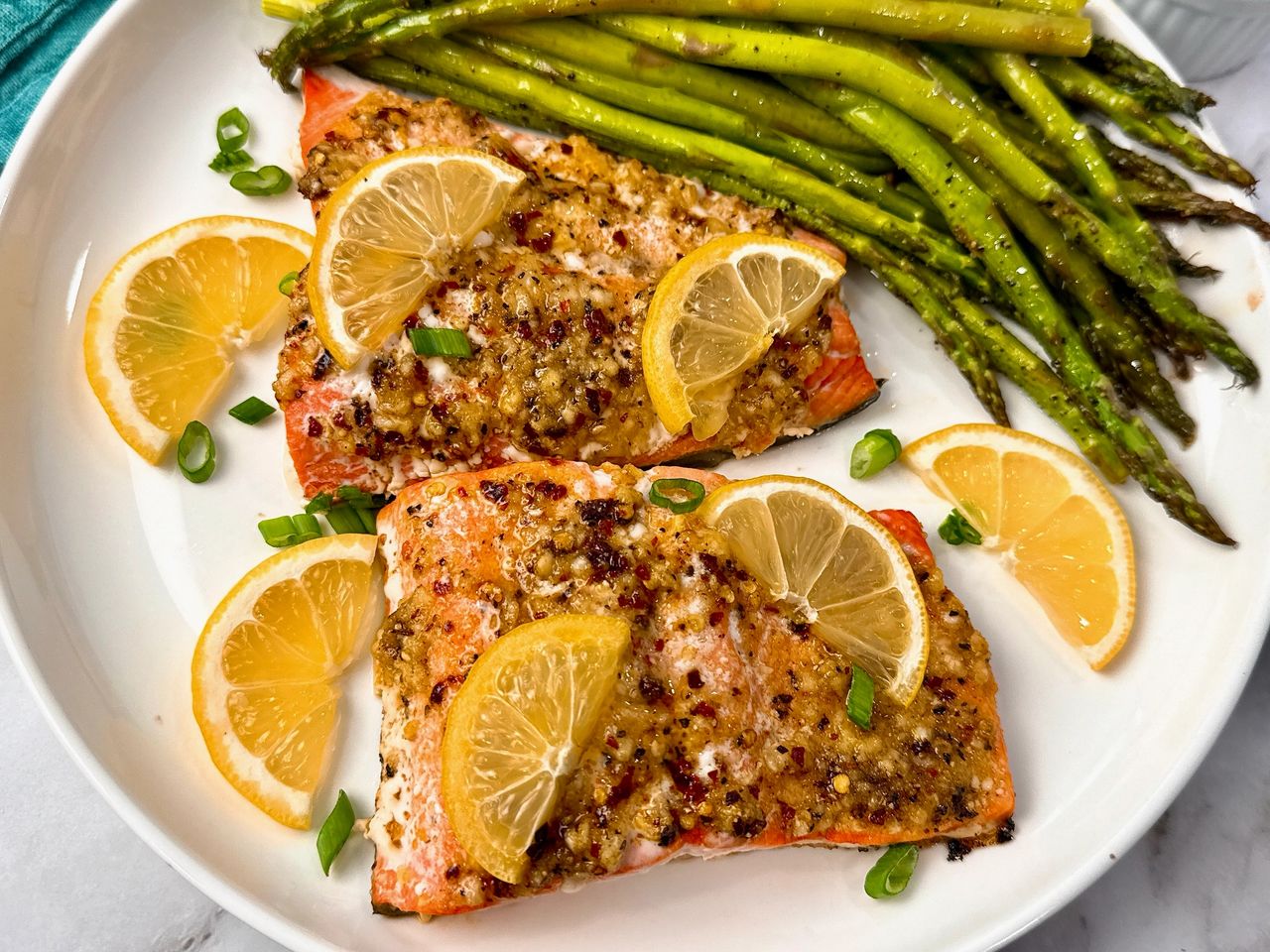 salmon on a white plate with lemon slices