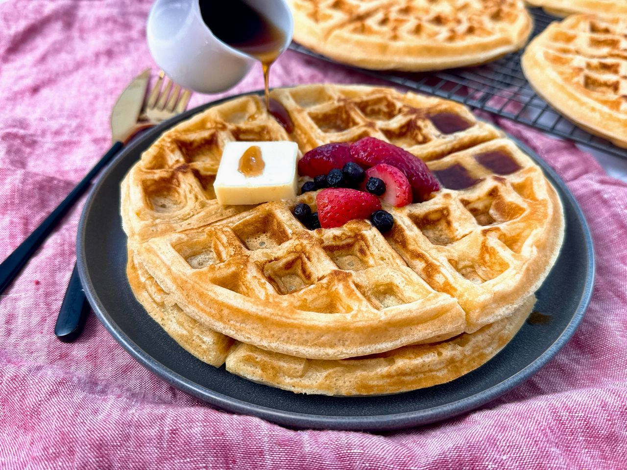 waffles on a grey plate with berries and butter
