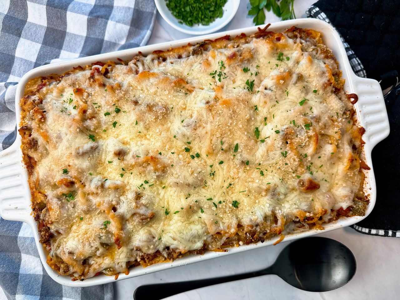 baked spaghetti in a baking dish with a black spoon
