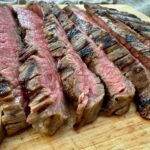 grilled flank steak slices on a wooden cutting board