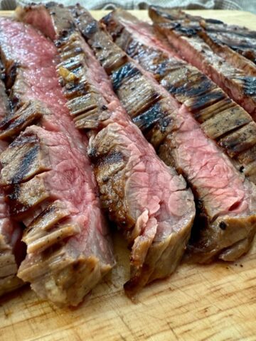 grilled flank steak slices on a wooden cutting board