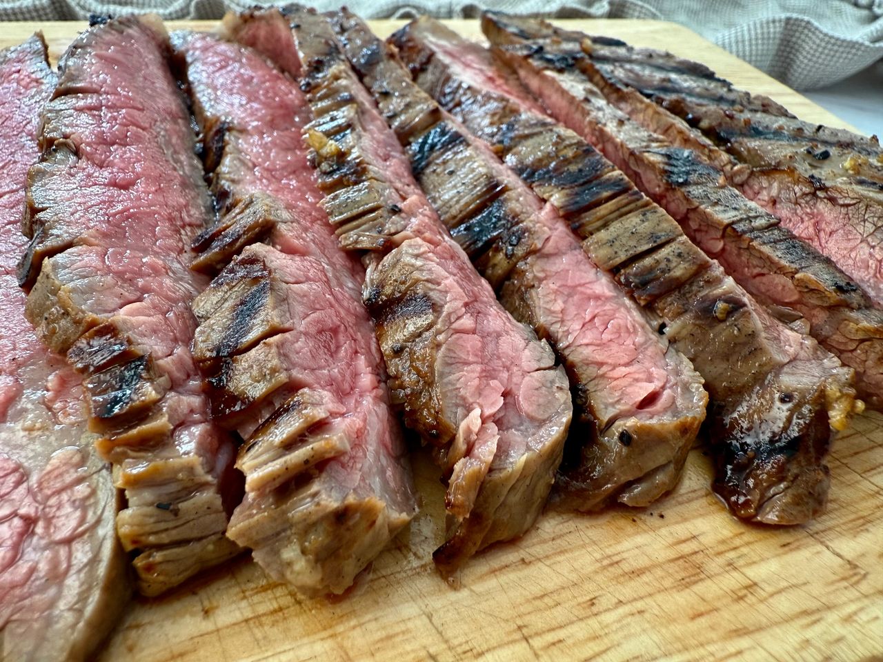 grilled flank steak slices on a wooden cutting board