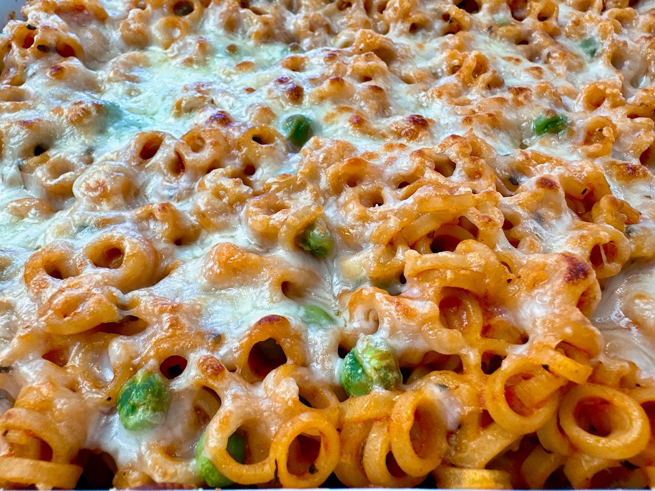baked pasta rings with sauce and cheese in a white casserole dish
