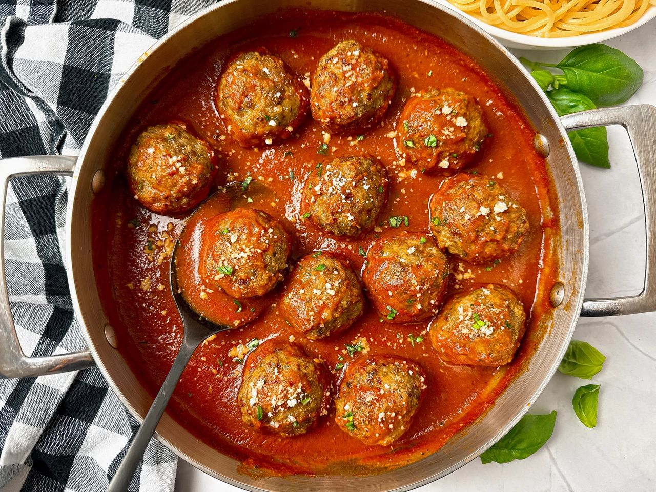 Italian Meatballs meatballs and marinara sauce in a pan with a black serving spoon