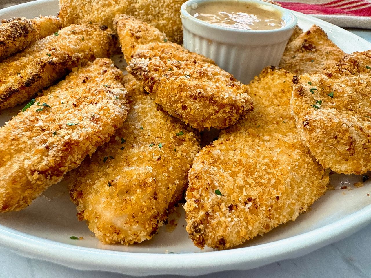 baked chicken fingers and honey mustard dip on a white plate