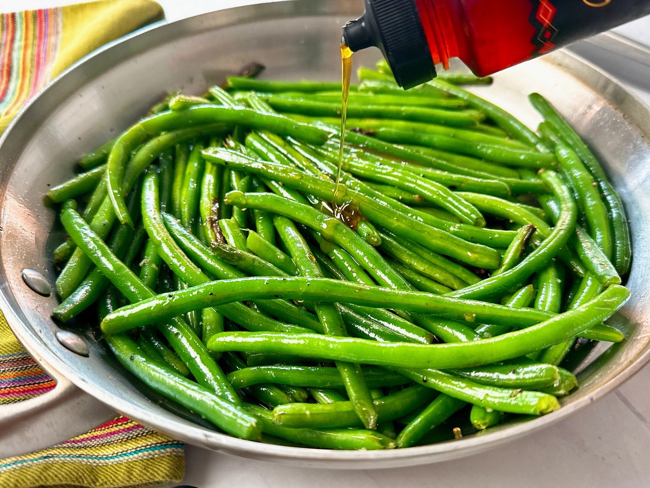 Hot Honey Green Beans green beans in a skillet being drizzled with hot honey