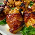 bacon wrapped chicken on a white plate with parsley garnish