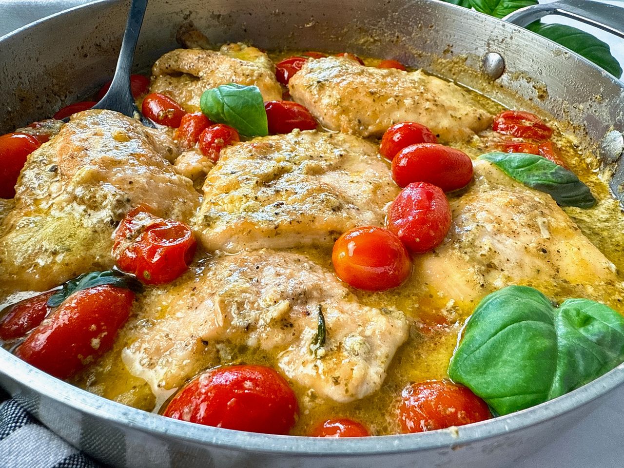 chicken and grape tomatoes with pesto in a silver pan