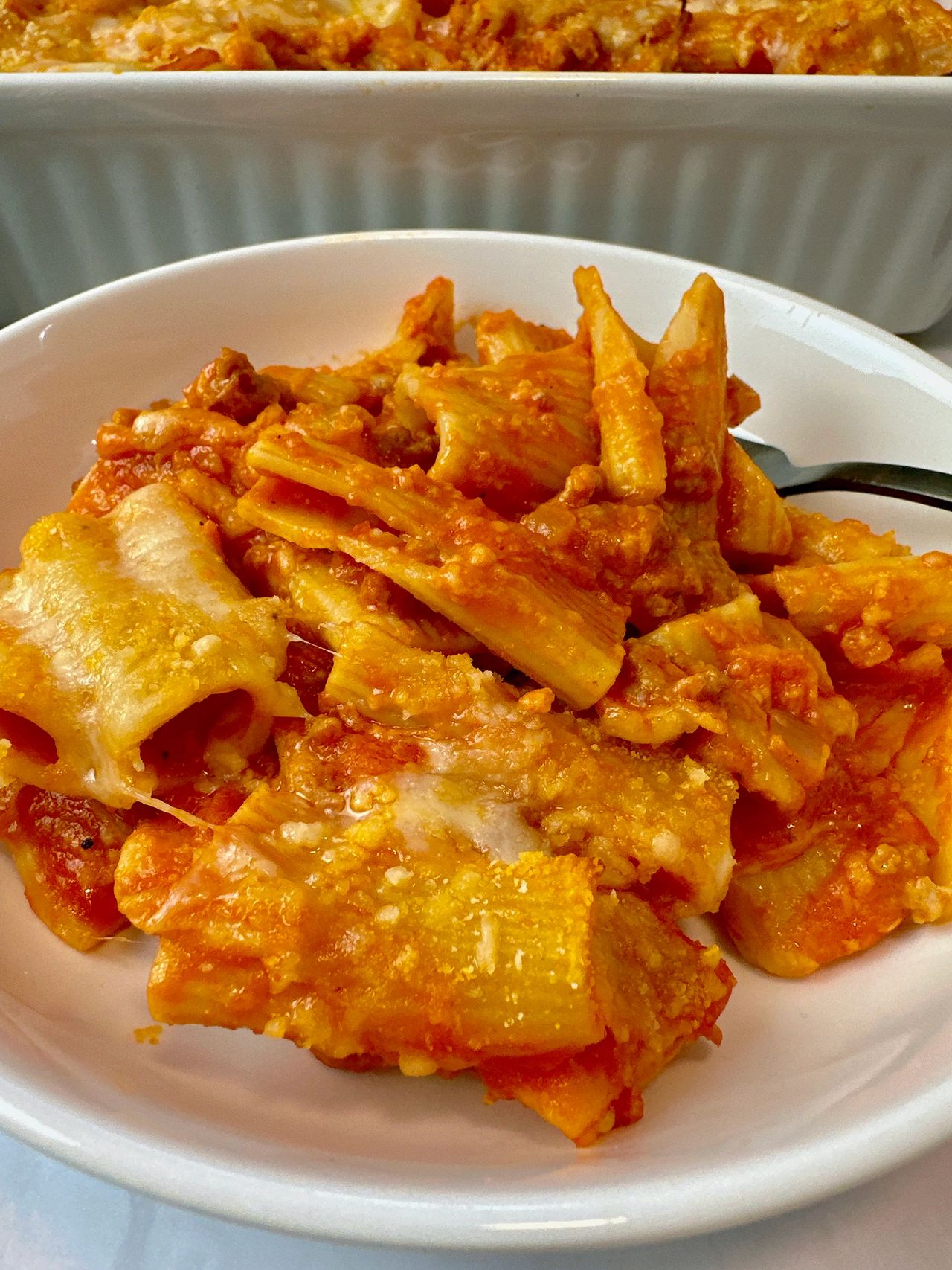 pasta and sausage in a casserole dish and white bowl