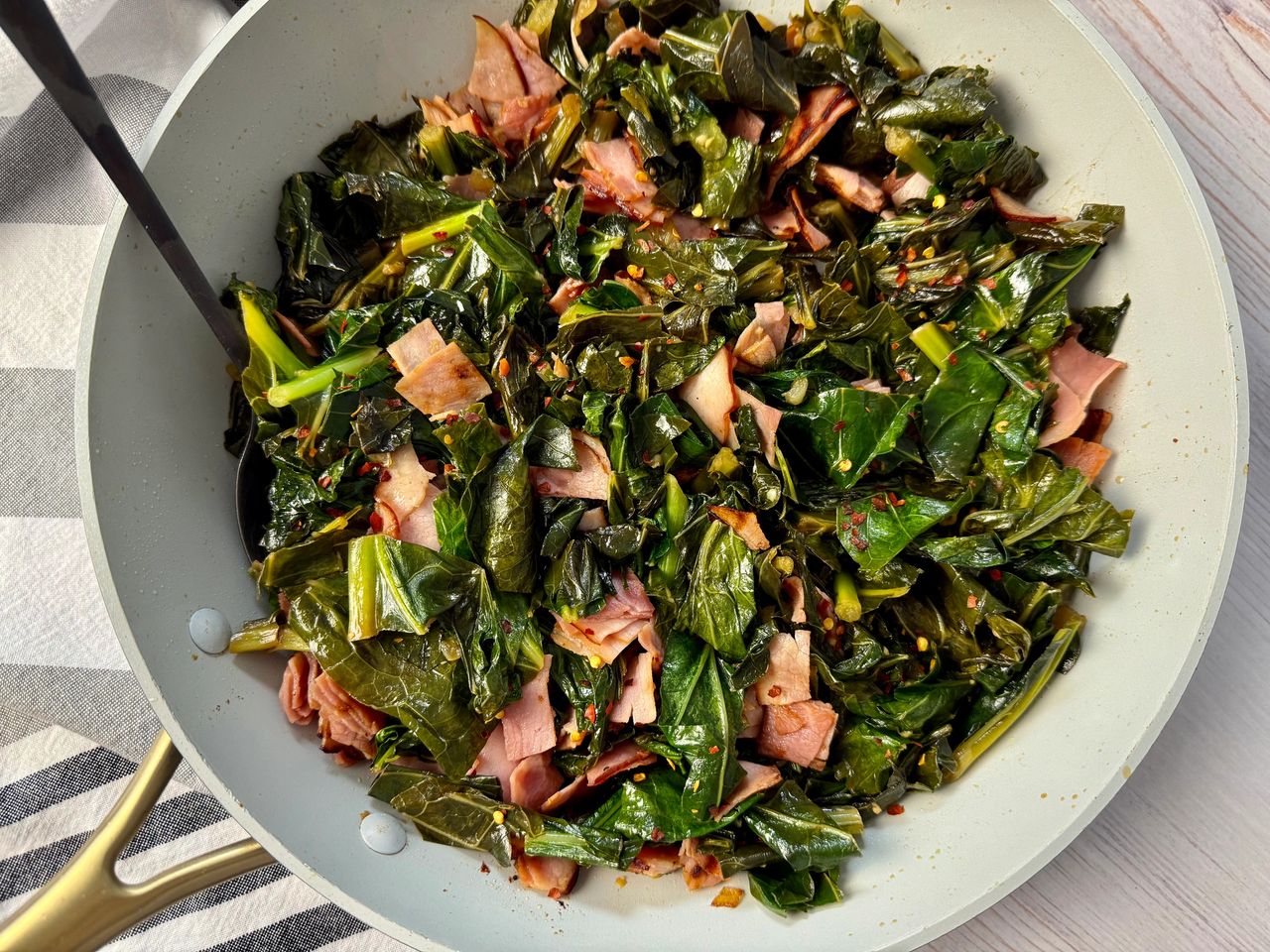 collard greens and ham in a white skillet