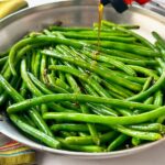 green beans in a skillet being drizzled with hot honey