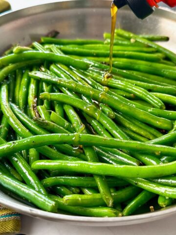 green beans in a skillet being drizzled with hot honey