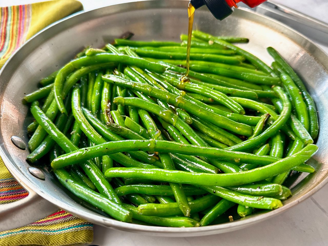 green beans in a skillet being drizzled with hot honey