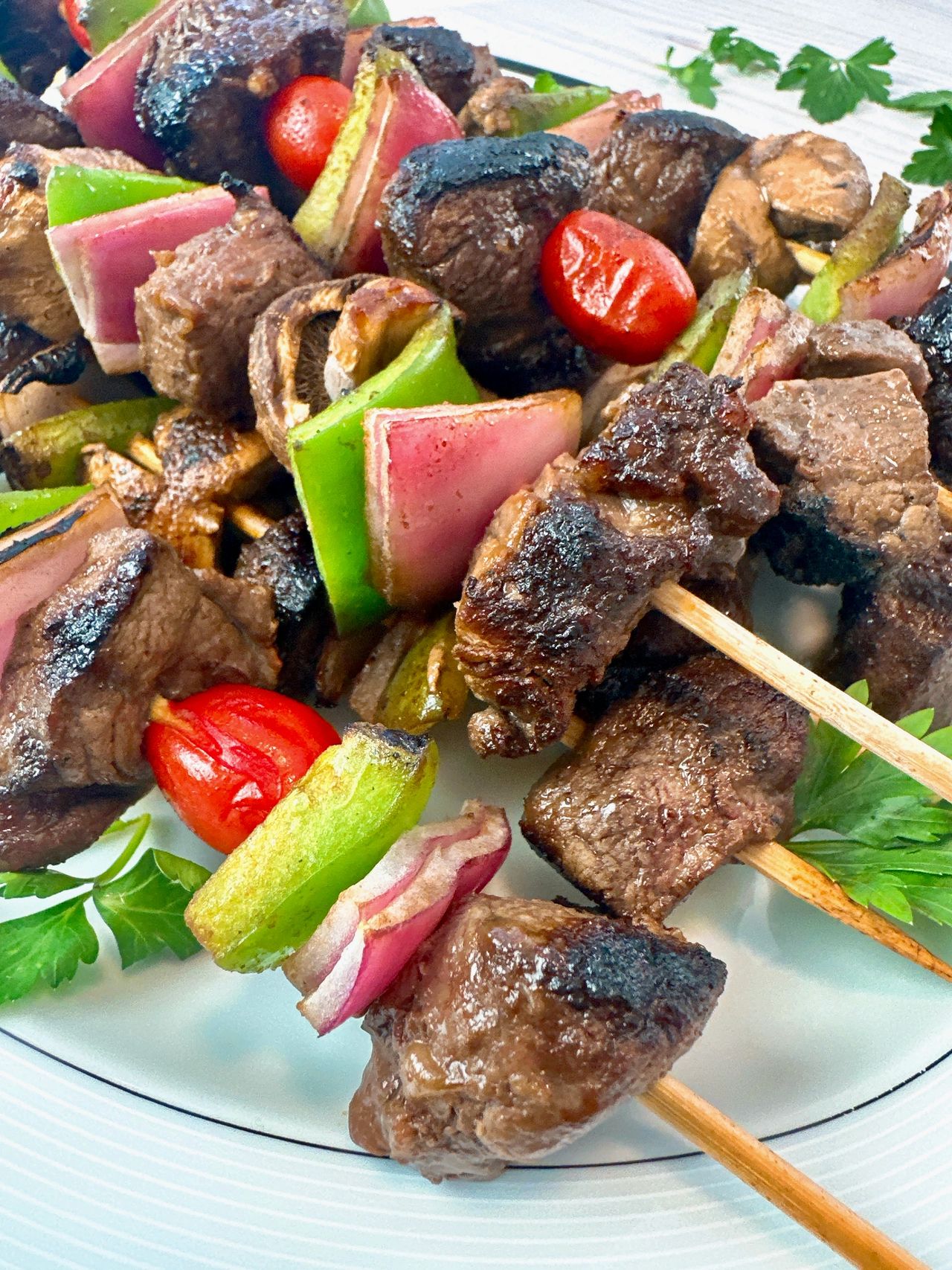 beef and vegetable kebabs on a white serving plate