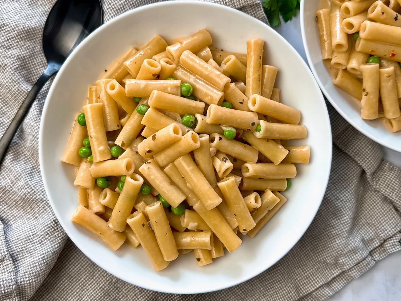 pasta and peas in a cream sauce in a white bowl