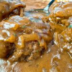 hamburger steaks and gravy with a black spoon