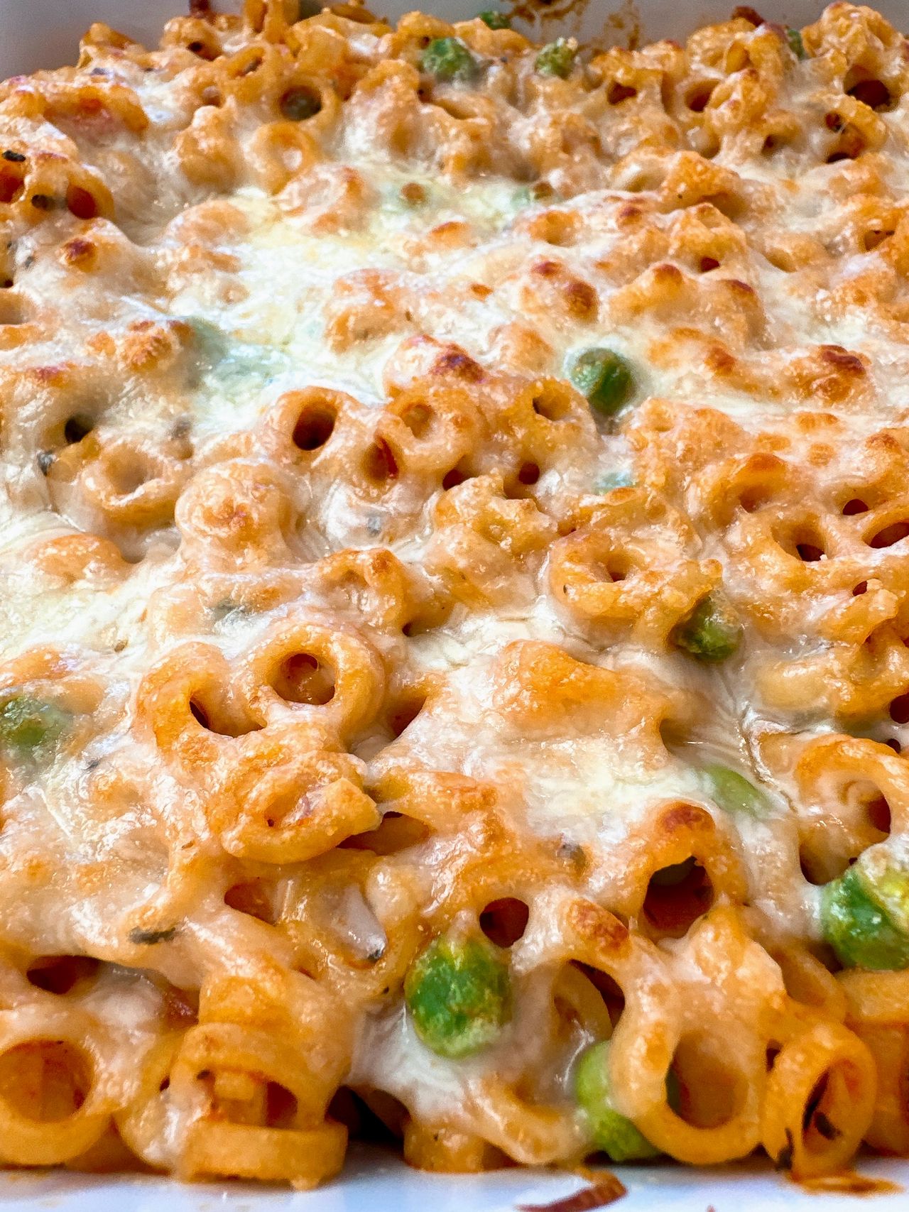 baked pasta rings with sauce and cheese in a white casserole dish