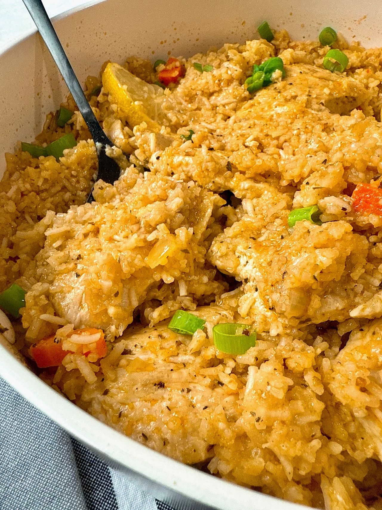 chicken and rice in a white saucepan with lemon garnish
