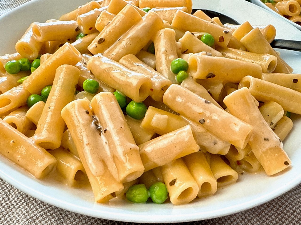 pasta and peas in a cream sauce in a white bowl