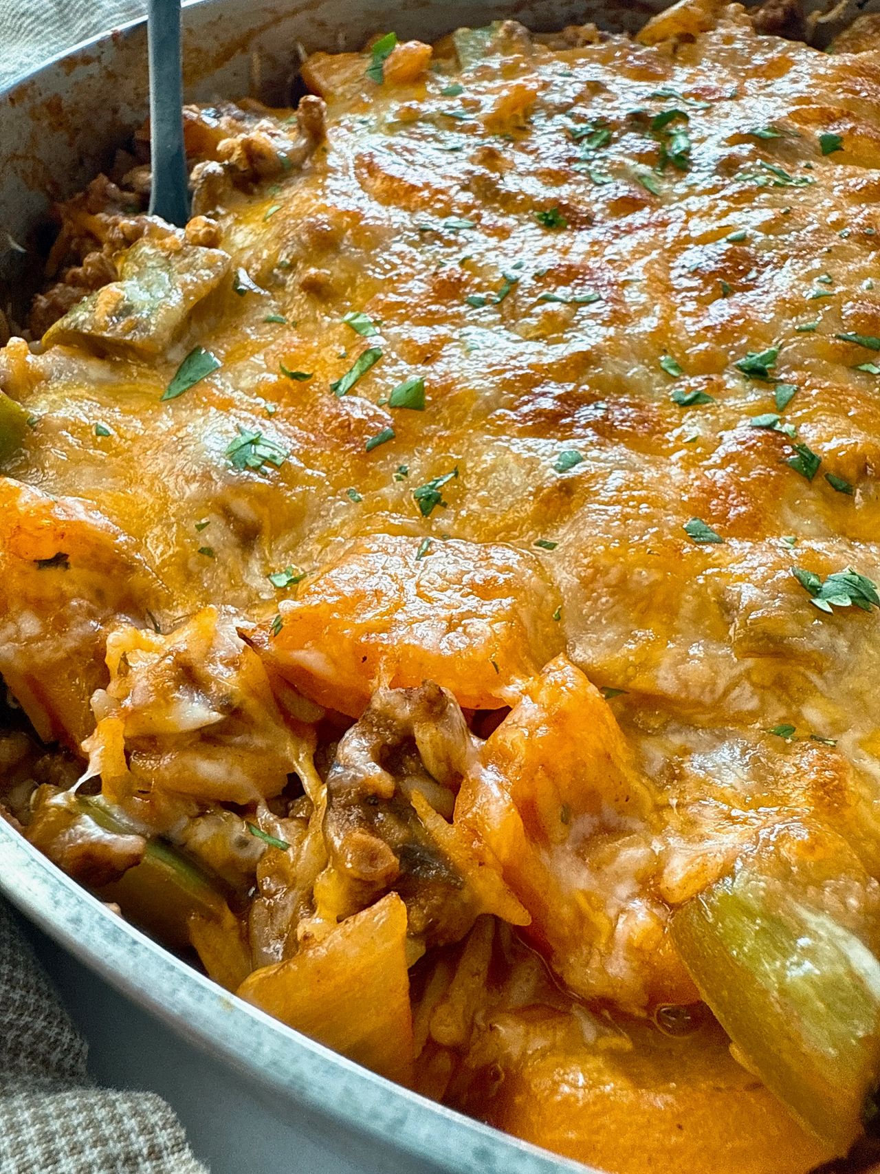 ground beef and rice covered with melted cheddar cheese in a deep skillet