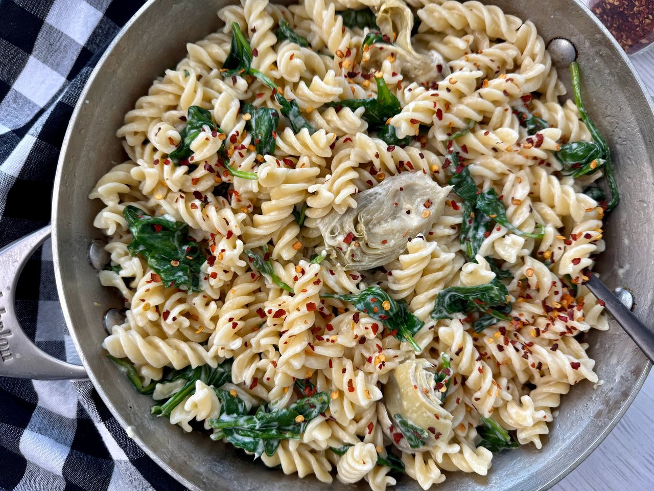 pasta with spinach and artichoke hearts in a skillet