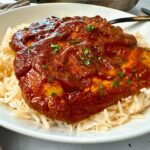 chicken with enchilada sauce over rice on a white plate