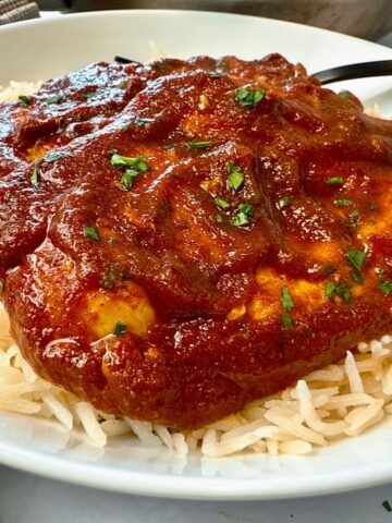 chicken with enchilada sauce over rice on a white plate