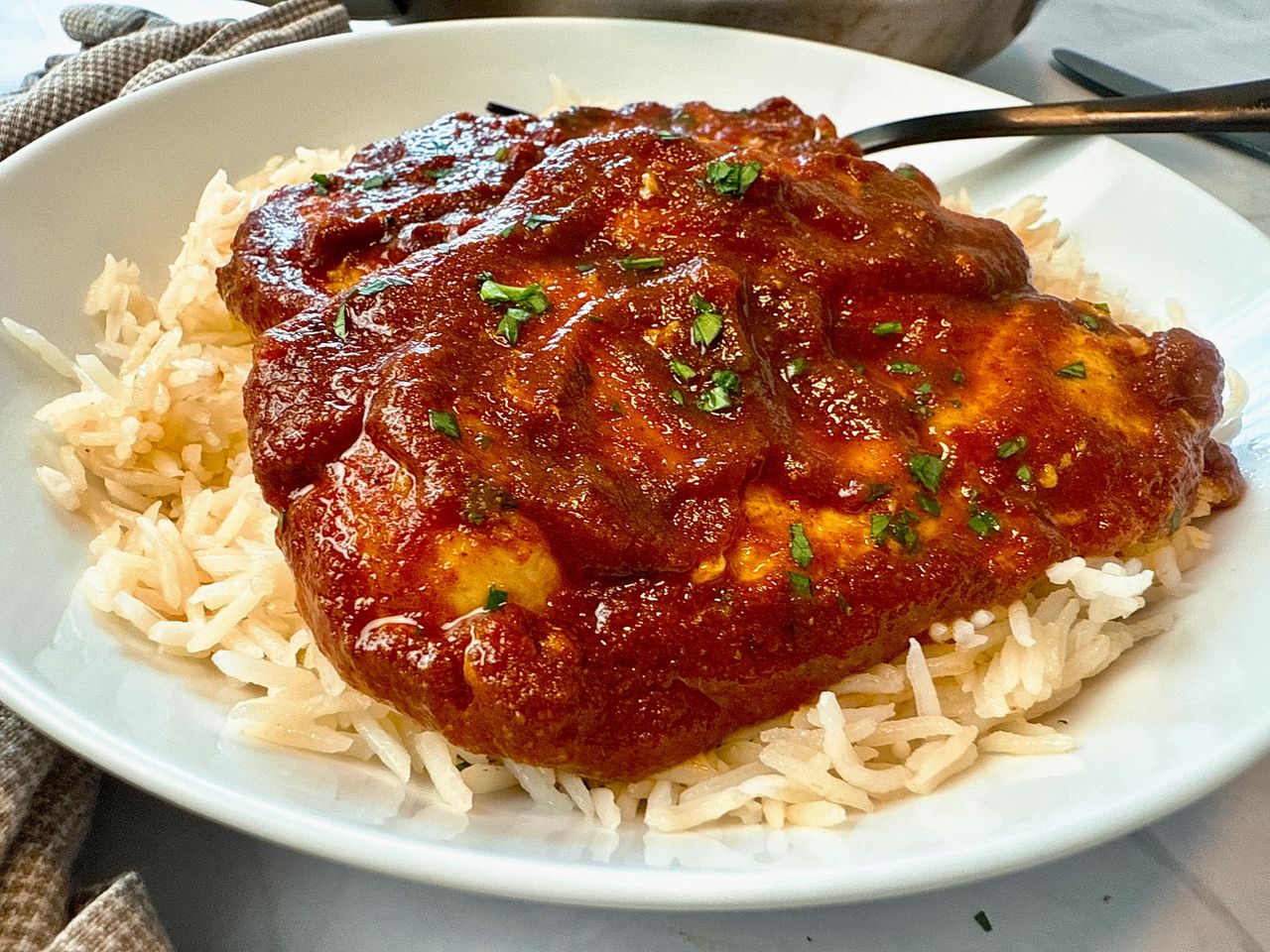 chicken with enchilada sauce over rice on a white plate