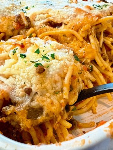 baked spaghetti in a baking dish with a black spoon