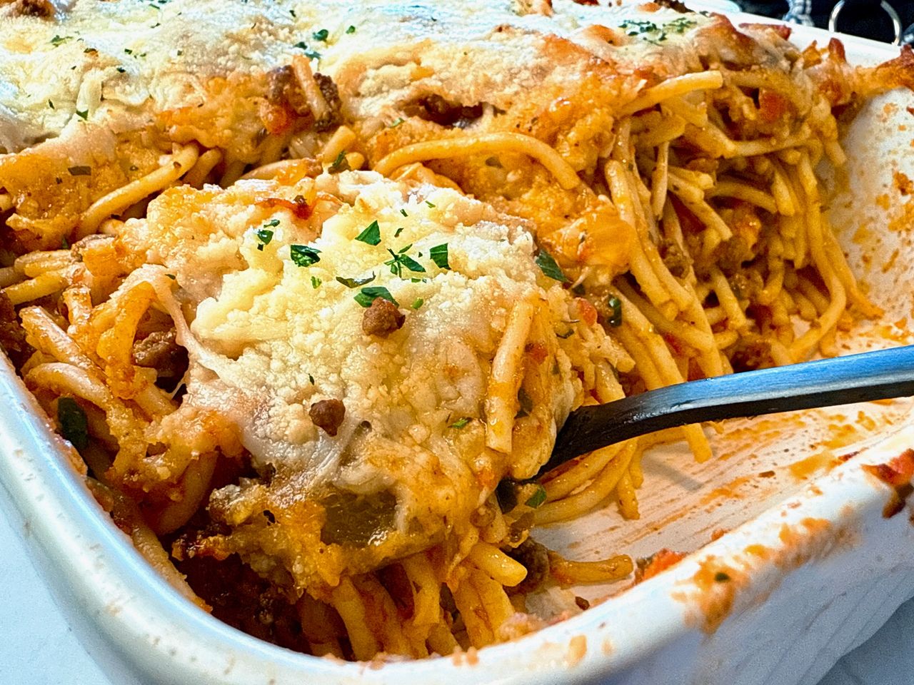 Baked Spaghetti baked spaghetti in a baking dish with a black spoon