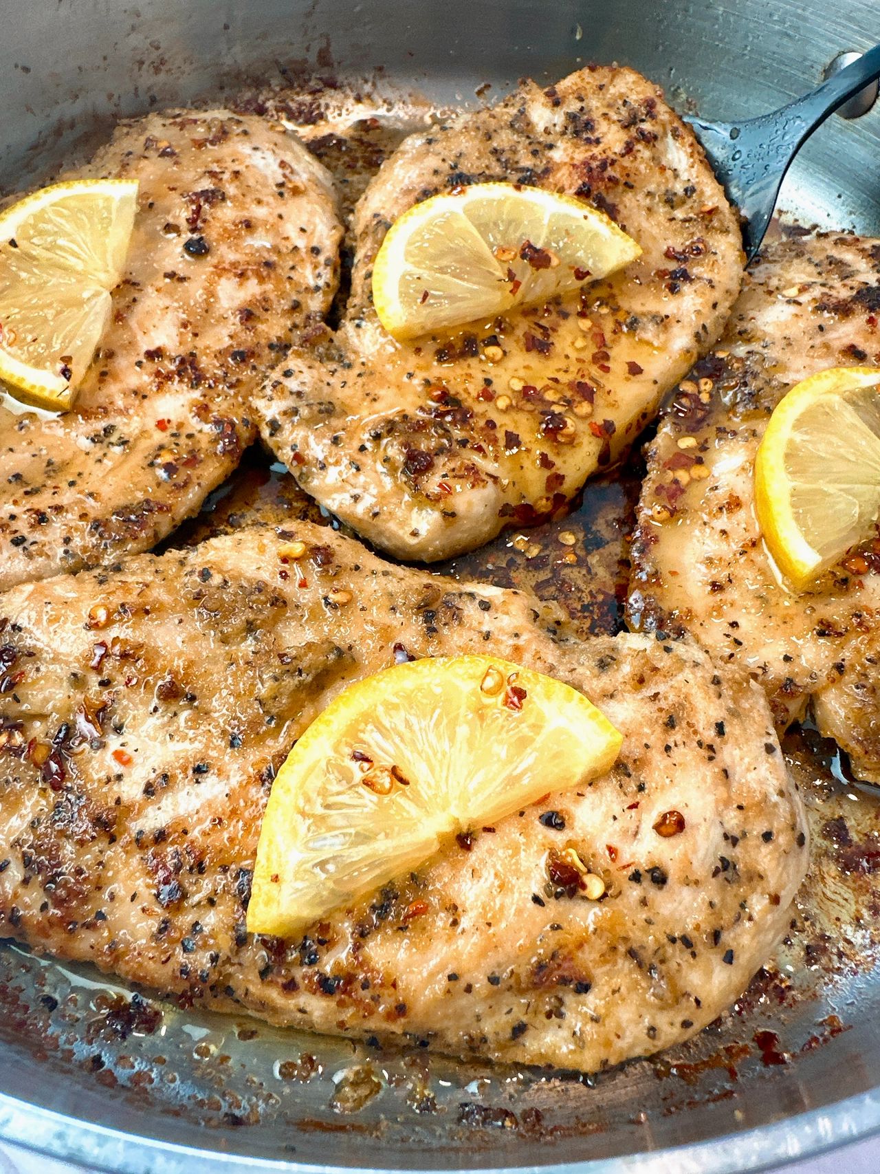 chicken and lemon in a skillet with a drizzle of honey