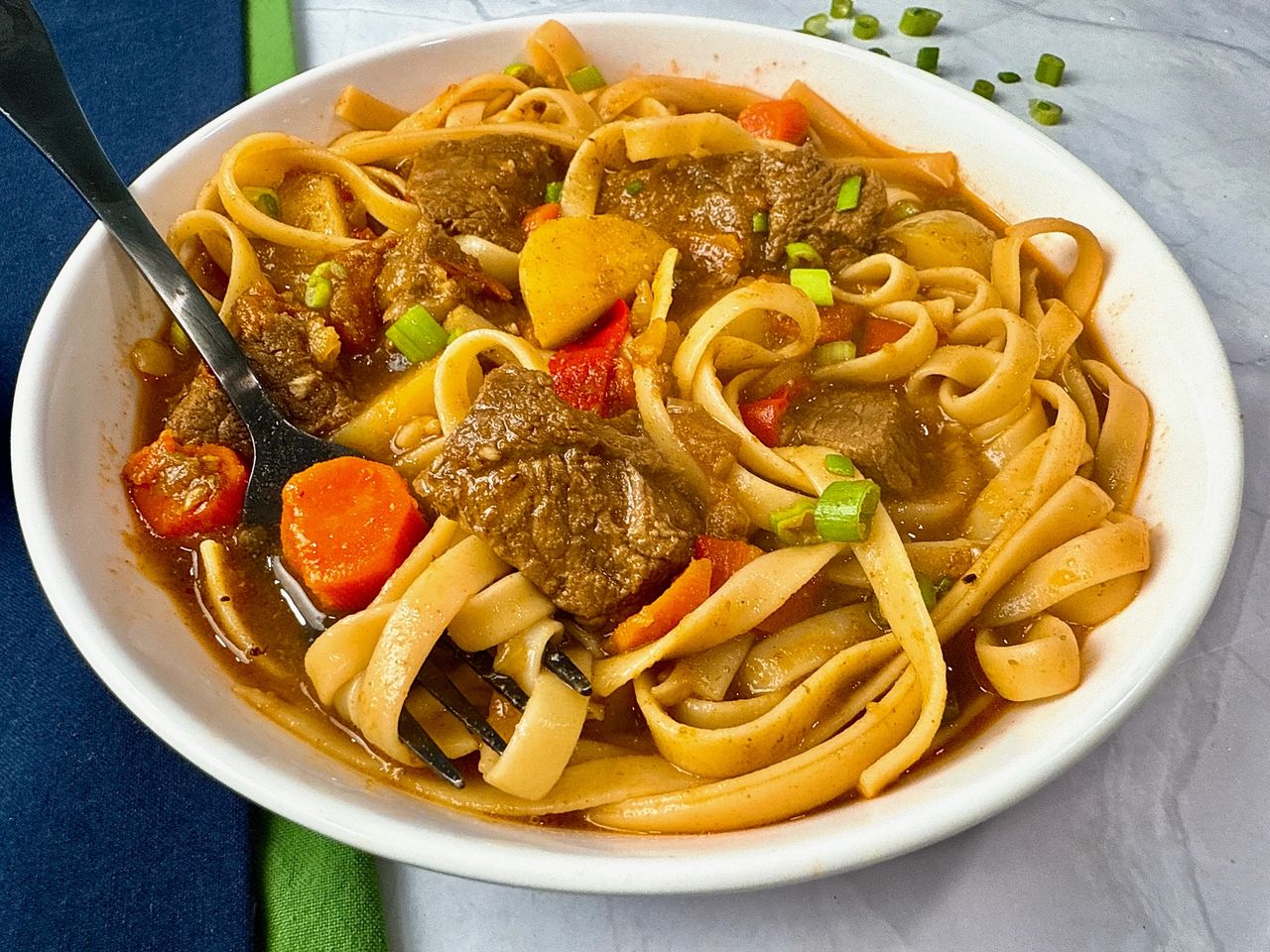 beef and noodle stir fry in a white bowl