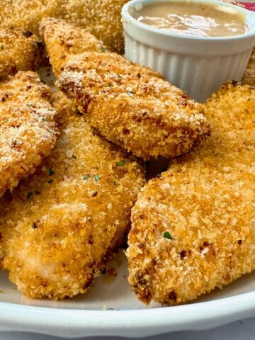 baked chicken fingers and honey mustard dip on a white plate
